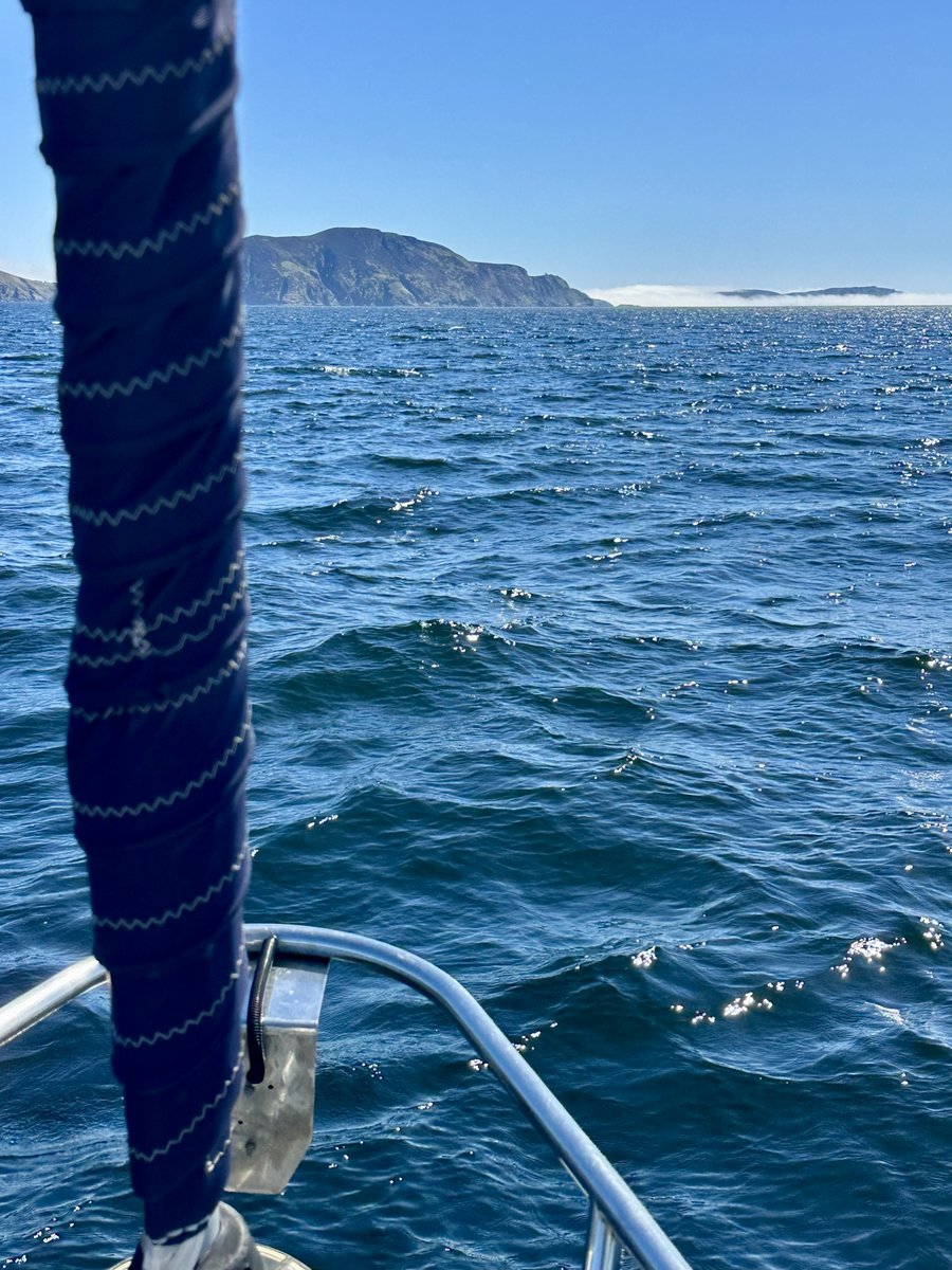Furled headsail, blue water, headland and sea mist