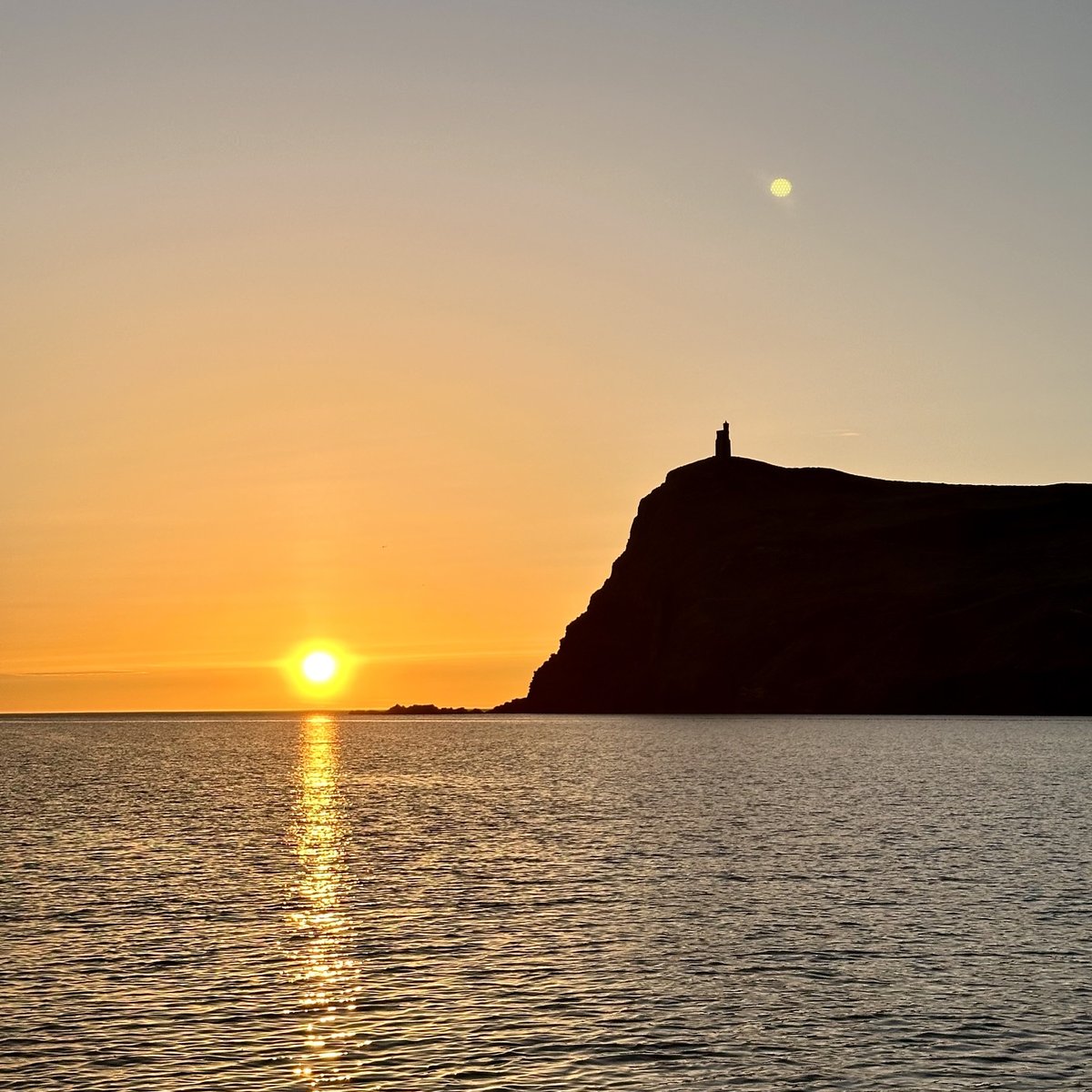 Sunset approaching Port Erin - burnt orange sky over Bradda Head, moon rising