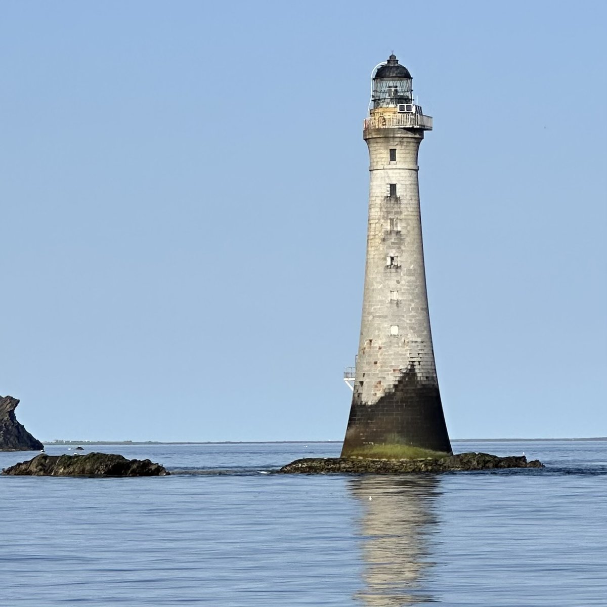Chicken Rock Lighthouse - the Stevenson lighthouse on the rock, with a small boat nearby