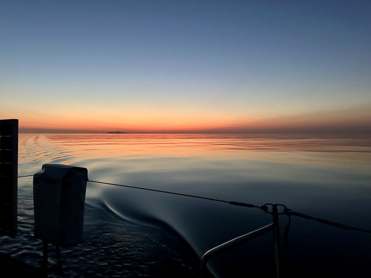 Sunrise from the stern - wake trailing, island silhouette on the horizon