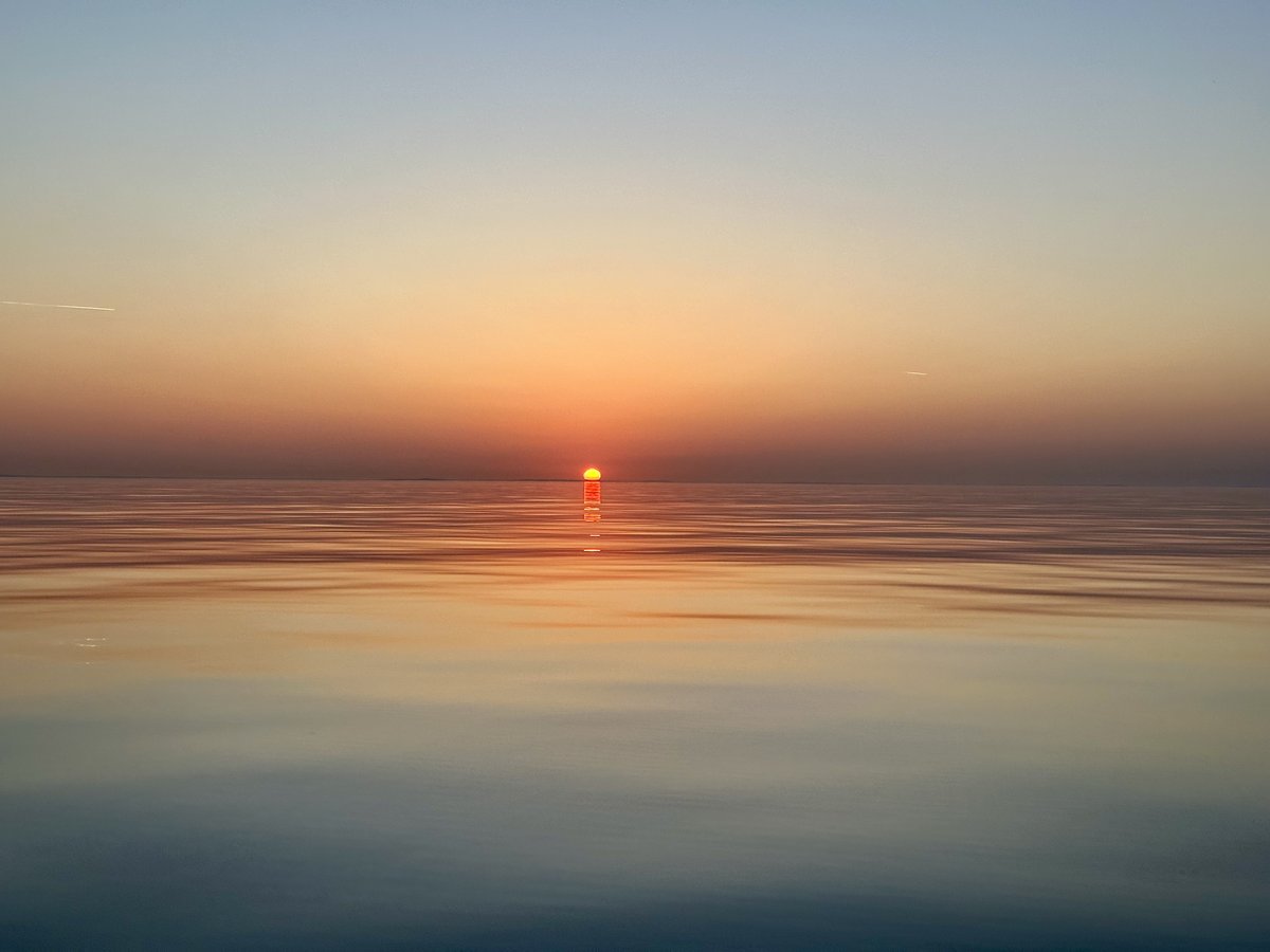 Sunrise - sun on the horizon, golden path on calm water