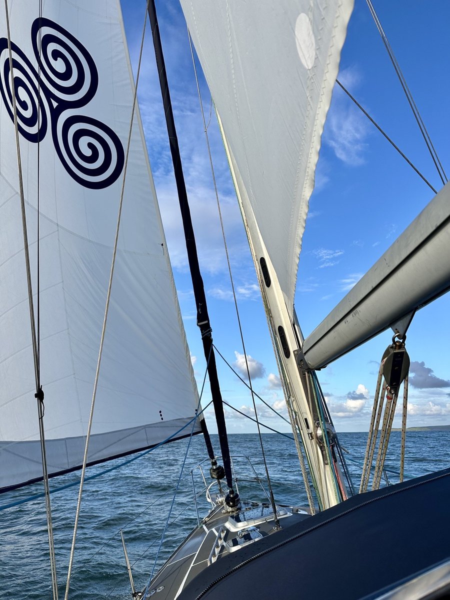 Sails filled with wind - triskelion logo on the sail, choppy blue sea