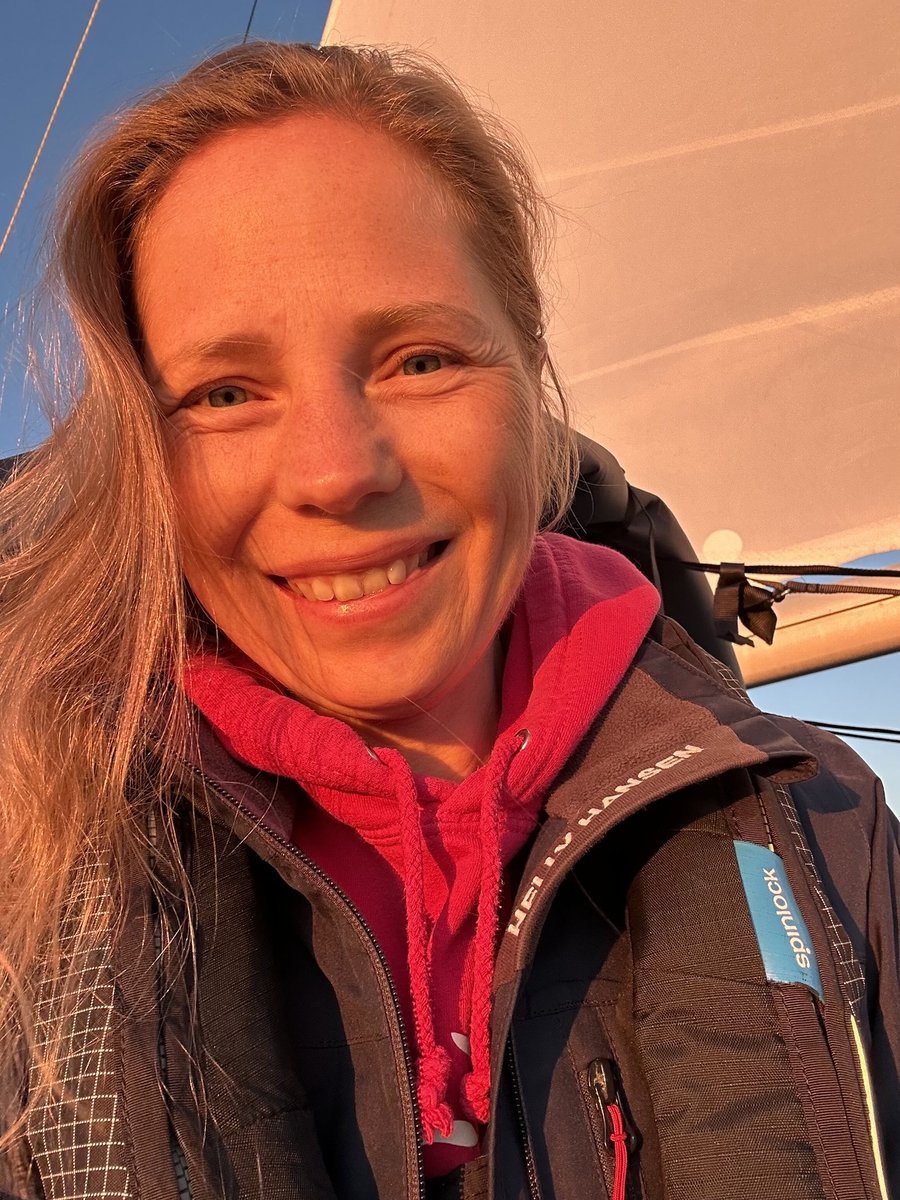 Andrea in golden hour light, sail behind her, warm evening glow
