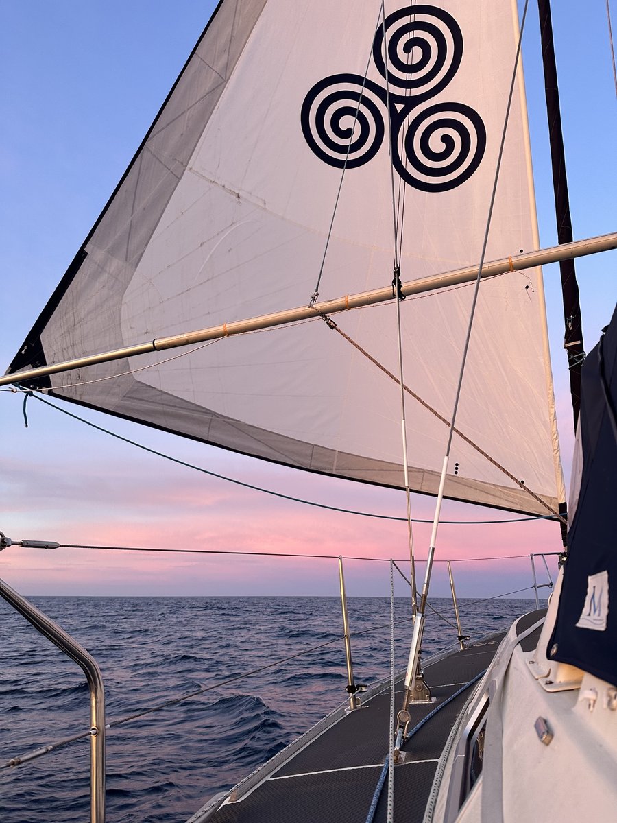 Triskelion sail from deck - sail taut with Celtic logo, golden hour sea